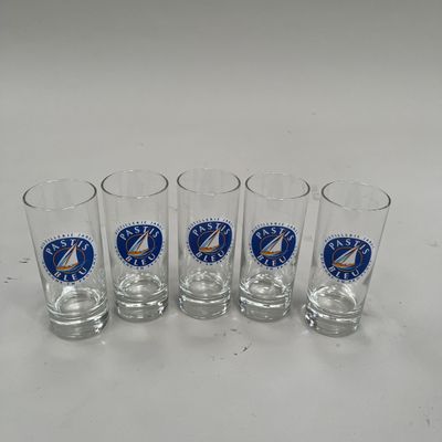 quatre verres à shot sont alignés sur une surface blanche