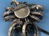 a silver brooch that has a bunch of glasses attached to it