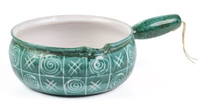 a green bowl with a spoon in it on a white surface