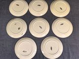 six white plates with black bugs on them sitting on a blue cloth