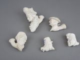 six petites figurines blanches représentant des personnes et des animaux, posées sur une surface grise