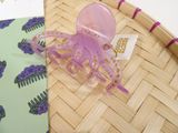a purple octopus hair comb sitting on top of a woven basket