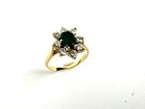 a close up of a ring with a green stone surrounded by diamonds
