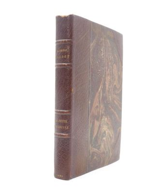 an old book with a brown cover sitting on top of a white surface