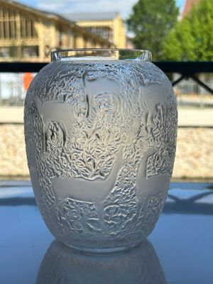 un vase en verre posé sur une table, avec un immeuble en arrière-plan