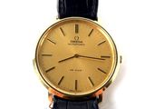 a gold watch with black leather straps on a white surface