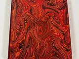 a red and black marbled notebook on a white surface