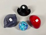 four different colored glass objects on a white surface