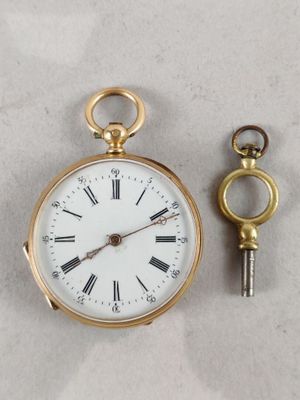 a gold pocket watch with a key attached to it
