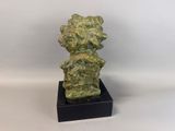 a green sculpture of a bear on a black base
