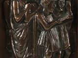 bronze relief of a group of people in a wooden frame