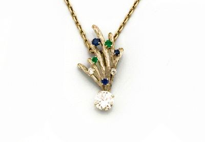 un gros plan sur un collier en or orné d'un diamant et de saphirs