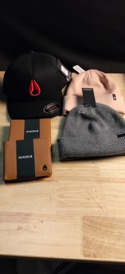several hats and a cell phone are sitting on a wooden table