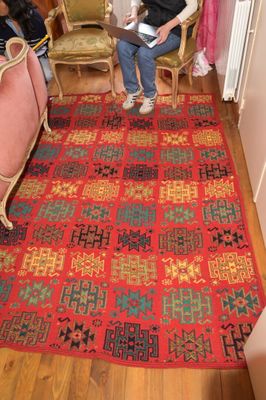 une femme assise sur un tapis dans une pièce