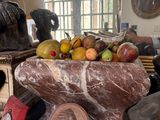 a bowl of fruit on a table next to a statue of a man