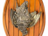 a metal bird on a wooden plaque mounted on a wall