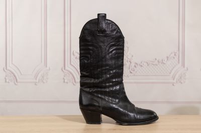 a pair of black cowboy boots sitting on top of a wooden table