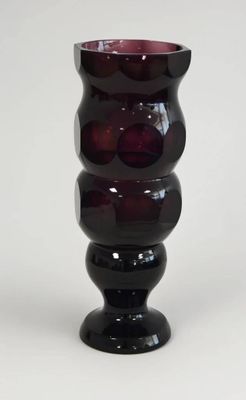 un vase noir et rouge posé sur une surface blanche