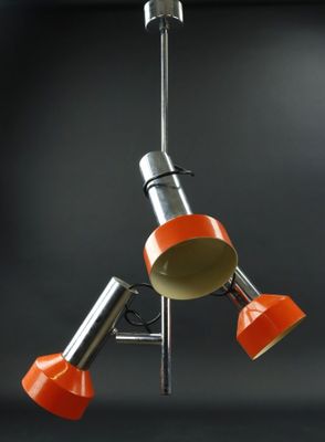 trois lampes orange suspendues au plafond d'une pièce sombre