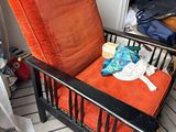a chair with an orange cushion in the corner of a room