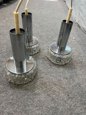 two silver vases with toothbrushes in them on the ground