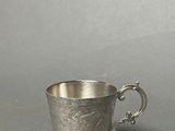 a silver cup with a handle on a table