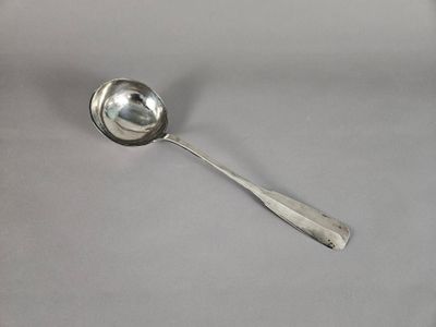 une cuillère en argent avec un manche de cuillère sur une surface blanche