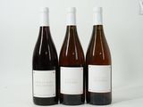trois bouteilles de vin posées les unes à côté des autres sur une surface blanche