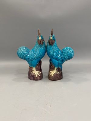 une paire de figurines de coqs en céramique bleue posées sur un fond blanc