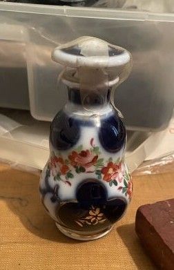 a small blue and white vase sitting on a table next to a brick