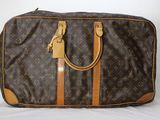 un sac Louis Vuitton marron et beige posé sur une surface blanche
