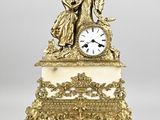 une horloge ancienne surmontée d'une statue représentant un homme et une femme