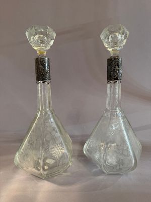 pair of clear glass perfume bottles with black tops on a white background