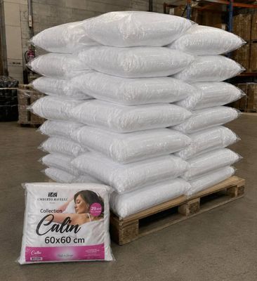 une pile d'oreillers posée sur une palette dans un entrepôt