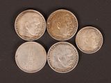 five different coins are arranged in a row on a black surface