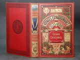 an old book with a red cover sitting on top of a table
