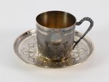 an antique silver cup and saucer on a silver plate