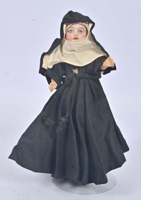 poupée représentant une religieuse en robe noire posée sur un fond blanc