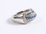 a close up of a diamond and sapphire ring on a white surface