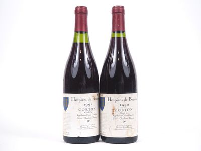 deux bouteilles de vin rouge posées l'une à côté de l'autre sur une surface blanche