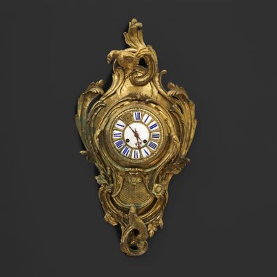 a gold clock on the wall with a bird on it