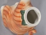 a ceramic teapot shaped like a cat with a green bow on its neck