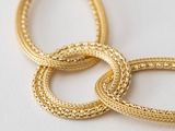 three gold hoop earrings on a white surface