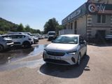 une voiture blanche garée devant un immeuble devant lequel sont garées d'autres voitures