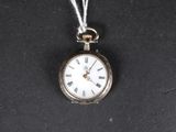 une petite montre de poche en argent avec une chaîne, posée sur une surface noire