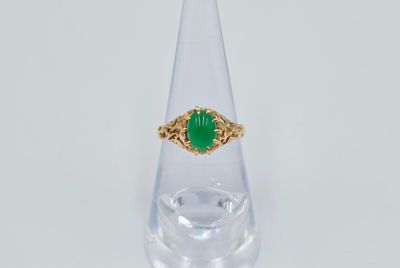 Gros plan sur une bague en or ornée d'une pierre verte