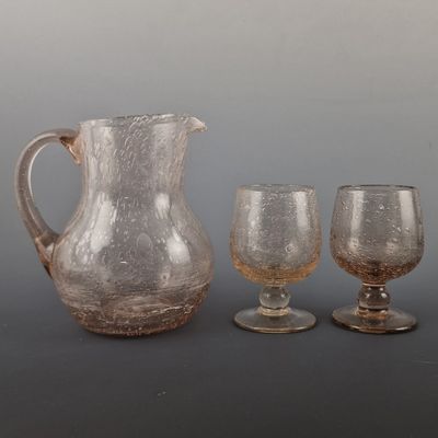 three glasses and a pitcher sitting next to each other on a table