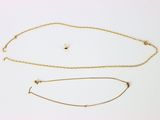 deux colliers en or et un bracelet posés sur une surface blanche