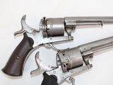 two revolvers on a white table with a black handle