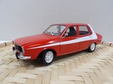 une petite voiture rouge et blanche posée sur un plancher en bois